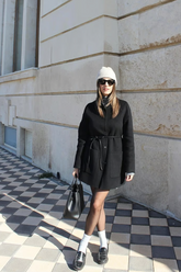 a lady wears a black wool coat as a mini dress